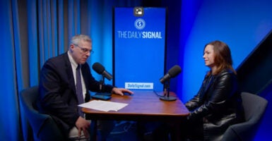 Jack Fowler sits at a table with Dr. Elizabeth Spalding against a blue backdrop and screen reading "The Daily Signal."