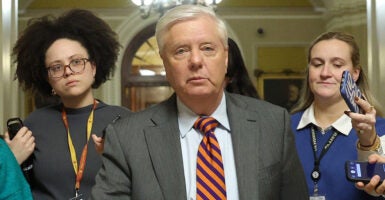 Lindsey Graham walks down a hall.
