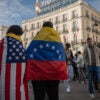 MADRID, SPAIN - 2026/01/03: A couple wearing the flag of Venezuela and the flag of the United States of America. Thousands of Venezuelans living in Madrid gathered at Puerta del Sol to celebrate the arrest of President of Venezuela Nicolas Maduro after President of the United States of America Donald Trump announced that US forces had captured Venezuela's leader after bombing Caracas. (Photo by Marcos del Mazo/LightRocket via Getty Images)