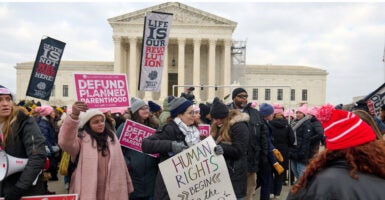 Pro-life activists stand with signs outside of the U.S. Supreme Court.