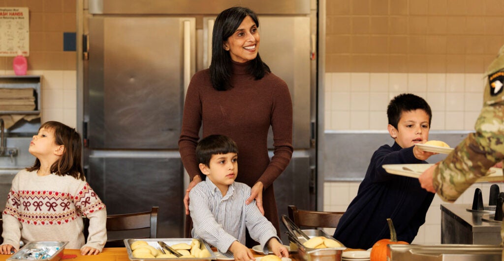Second Lady Usha Vance places her hands on her son's shoulders as he serves military members their food.