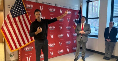 Vivek Ramaswamy gestures to the crowd with a campaign banner behind him.