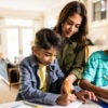 Mother helping tween sons with homework in kitchen