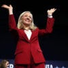 Abigail Spanberger in a red suit with her arms raised.
