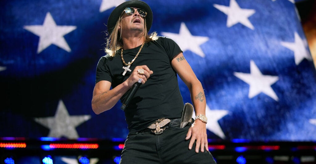 Kid Rock performs at Republican National Convention in front of large screen of American flag.