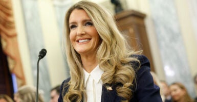 A smiling Kelly Loeffler in blue jacket at hearing.