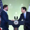 JD Vance and Marco Rubio shake hands behind a podium