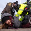 A female protester is held down by police and handcuffed.