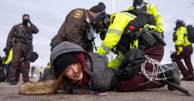 A female protester is held down by police and handcuffed.