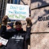 A male demonstrator holds a sign reading "Don't Gut the Newsroom. Save the Post" outside the Washington Post building.