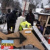Anti-ICE protesters stand behind a makeshift barrier blocking a Minneapolis street.