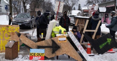 Anti-ICE protesters stand behind a makeshift barrier blocking a Minneapolis street.