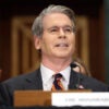 Scott Bessent smiles while testifying at a hearing.