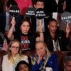 Democrat members of congress hold up signs and look on in anger during President Trump's 2025 address to Congress.