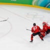 Team USA's Jack Hughes scoring winning goal against Canada, with puck going past goalie.