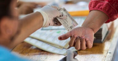 LA PAZ, MEXICO - JUNE 06: A polling official marks a voter's thumb with indelible ink and hands him his voter ID on June 6, 2021 in La Paz, Mexico. A record number of 93.5 million citizens are able to vote today in the largest election in the country's history. 500 deputies, governors in 15 states and 20,000 local authorities will be elected. During the campaign, 35 candidates were reported murdered. (Photo by Alfredo Martinez/Getty Images)
