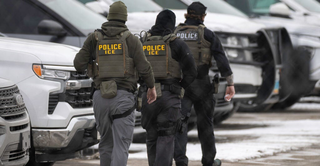 Three ICE officers are seen walking away in the snow.
