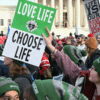 People hold "Love Life - Choose Life" signs in front of the US Supreme Court as they march in the 53rd annual March for Life rally in Washington, DC, on January 23, 2026. The annual pro-life demonstration, themed "Life is a Gift," marks the anniversary of the Roe v. Wade decision and includes a march toward Capitol Hill. (Photo by SAUL LOEB / AFP via Getty Images)