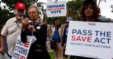 Supporters of the SAVE Act stand with their signs, including one reading, 