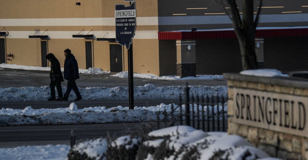Residents walk by a sign for Springfield, Ohio in the snow.