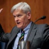 Sen. Bill Cassidy sits in a Senate hearing with his hands up.