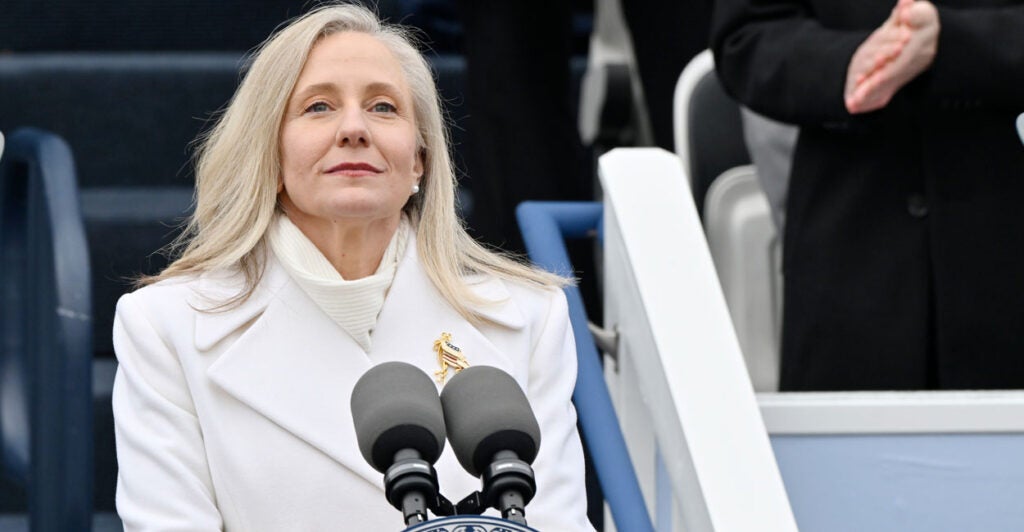 Abigal Spanberger in a white coat stands in front of microphones.