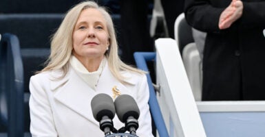 Abigal Spanberger in a white coat stands in front of microphones.