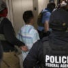 Federal agents lead a suspected illegal immigrant down a hallway.