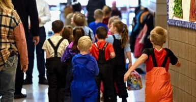 Elementary school students walking through a hallway.