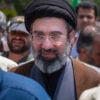 Mojtaba Khamenei, son of the late Iranian Supreme Leader Ali Khamenei walks amid a crowd of people.