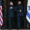 Benjamin Netanyahu and Donald Trump walk with arms on each other's back into doorway flanked by American and Israeli flags.