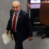 High angle shot of Benjamin Netanyahu walking through parliament with a folder.