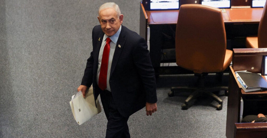 High angle shot of Benjamin Netanyahu walking through parliament with a folder.