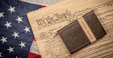 A Bible lays on a copy of the Constitution atop a flag.