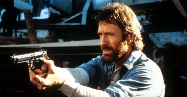 Chuck Norris points a gun in a scene from the film 'Hero And The Terror', 1988. (Cannon/Getty Images)