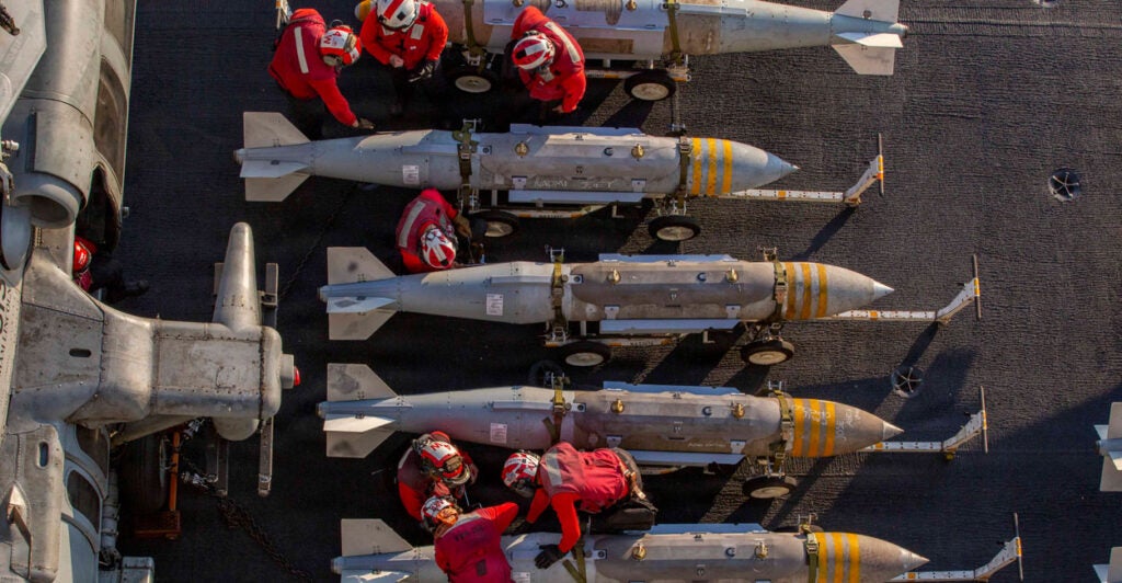 Overhead shot of U.S. Navy crew members inspecting a row of ordinance.