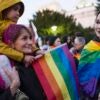 One adult woman and two female children holding rainbow flags.
