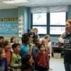 A female first grade teacher with students in a classroom.
