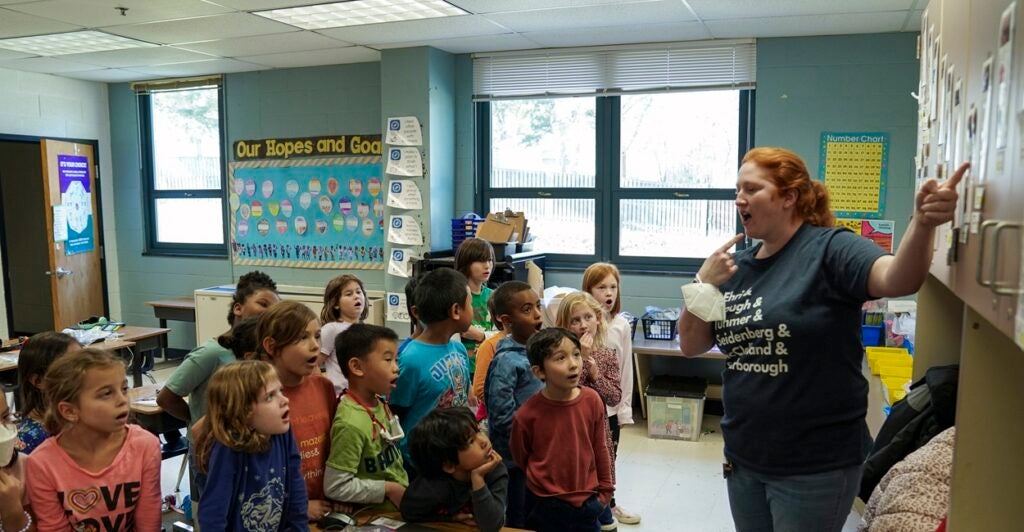 A female first grade teacher with students in a classroom.