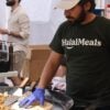 Man wearing shirt that says "halal meats" while cooking.
