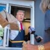 Donald Trump holding McDonalds bags out a window.