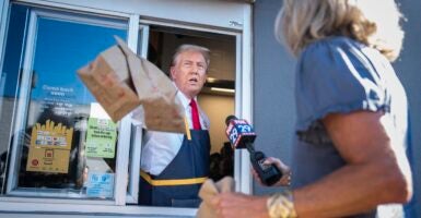 Donald Trump holding McDonalds bags out a window.