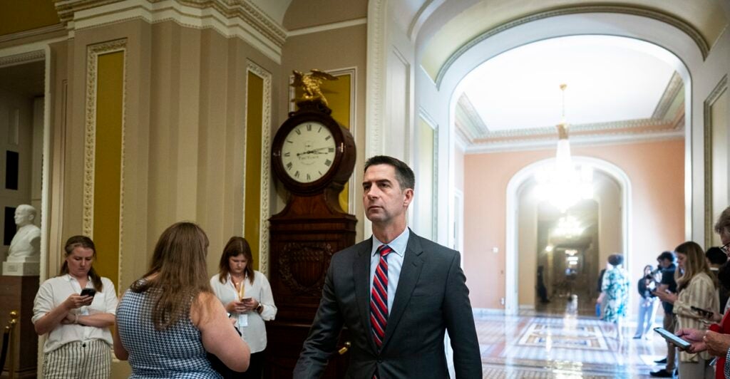 Sen. Tom Cotton walking past a clock.