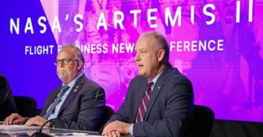 Two men sitting at a table in front of the words 