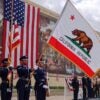 Uniformed men at a Veterans Day observance with a California flag.