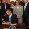 President Barack Obama signing a bill surrounded by people.