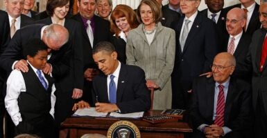 President Barack Obama signing a bill surrounded by people.