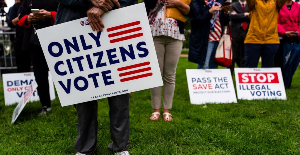 Supporters of the SAVE Act stand with signs, including, "ONLY CITIZENS VOTE."