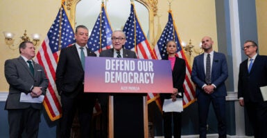 Chuck Schumer and others stand behind a podium which reads 