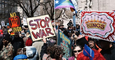 No Kings protest in New York filled with protesters and signs and a trans flag.